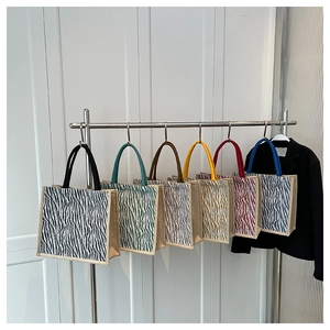 Close-up of zebra pattern tote bags in six different colored handles on display hooks