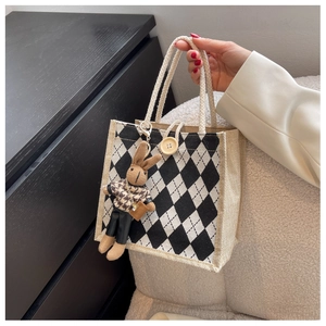 Detail of argyle pattern burlap tote bag with cute knit bunny charm and rope handle