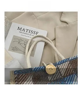 Detail of plaid linen tote bag with cream cotton rope handle and wooden button accent