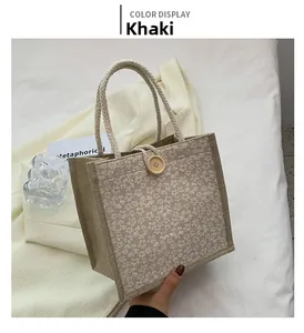 Detail of khaki woven tote bag with white daisy print and wooden button closure