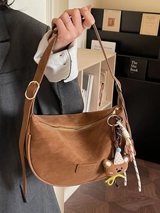 Vintage brown suede hobo bag with a plush bear charm and adjustable shoulder strap