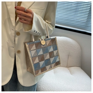 Detail of checkered canvas tote bag with wooden button and rope handle on a model