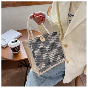 Detail of checkered jute tote bag featuring white rope handle and wooden button closure
