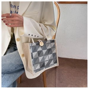 Detail of checkered linen handbag with woven texture and wooden button closure