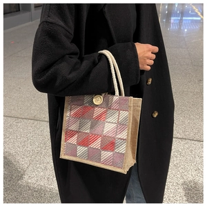 Detail of red and grey plaid woven tote bag with white rope handles and wooden button
