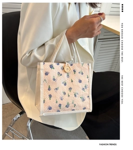 Detail of floral lace handbag with blue flower print, wooden button and woven handles