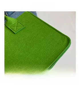 Detail view of vibrant green felt tote bag showing cross-stitched reinforced handle seams