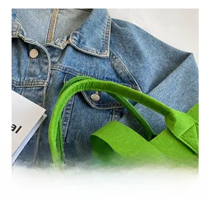Close-up of vibrant green felt tote bag showing durable wide handles and thick stitching