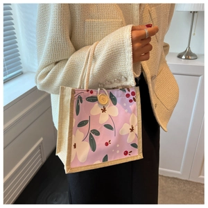 Détail du sac à lunch floral avec poignées tressées et fermeture décorative en bois