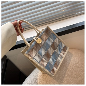 Detail of checkered woven linen handbag with large yellow button and rope handle