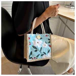 Détail du sac à lunch en toile florale avec bords en jute et bouton rond en bois