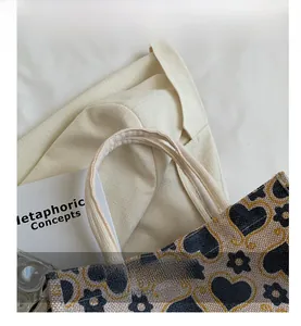 Detail of reinforced woven handle and floral heart pattern on canvas tote bag