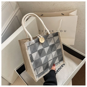 Close-up of a plaid linen mini tote bag with white rope handles and wooden button detail