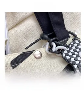 Detail showing checkered heart pendant and silver snap button on striped canvas bag