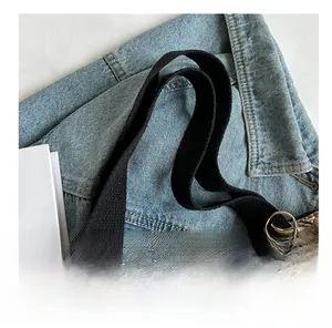 Close-up of ethnic canvas tote bag showing black shoulder strap and golden metal hardware