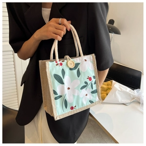 Détail du sac à lunch en jute avec imprimé floral, bouton en bois rond et anses en corde