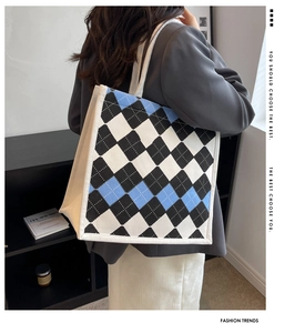 Detail view of large argyle tote bag with blue and black patterns and woven handle
