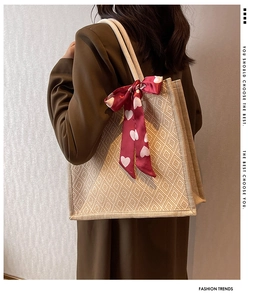 Detail of geometric woven tote bag featuring a red heart print silk scarf on handle