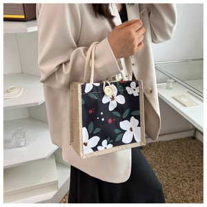 Détail du sac à lunch avec imprimé floral, côtés en jute et fermeture à bouton blanc
