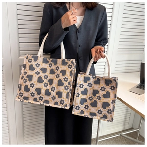 Detail view of large and small canvas tote bags with heart patterns and rope handles