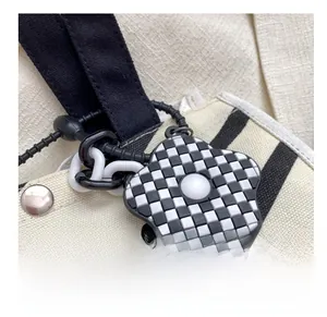 Detail of checkered flower charm with beaded chain on a minimalist canvas bag strap