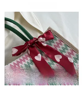Détail du sac cabas tressé avec motifs de vagues rose et vert et foulard en soie à cœurs