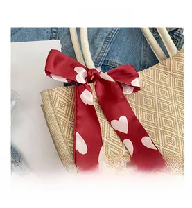 Detailed close-up of a woven tote bag featuring a red heart-patterned silk bow accent