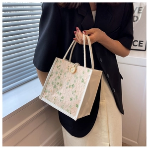 Detail of floral lace embroidery and cotton rope handle on this cream tote bag