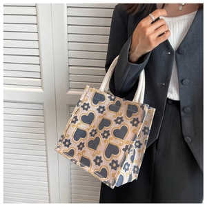 Detail view of woven tote bag with grey heart patterns and white rope handles