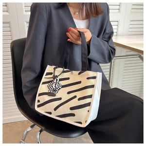 Detail of canvas tote bag with zebra stripes and checkerboard pendant charm