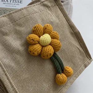 Detailed close-up of a woven tote bag featuring a 3D yellow knit flower decoration