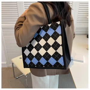 Shoulder shot of large argyle knit tote bag with blue and black diamond pattern