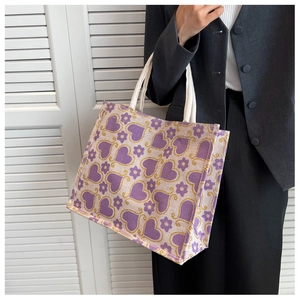 Detail of floral tote bag with purple heart patterns and white rope handles