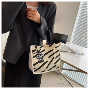 Detail of canvas mini tote bag with diagonal pattern and checkered bear charm accessory