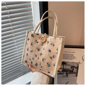 Floral canvas lunch bag with lace overlay and woven handles in a lifestyle setting