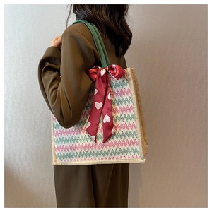 Détail du cabas en lin avec motifs zigzag rouge-vert et écharpe en soie décorative à nœud