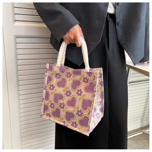 Macro detail of canvas tote bag showing purple hearts, yellow florals and rope handle