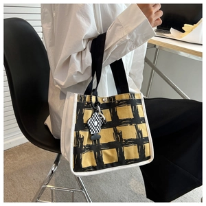 Detail of yellow and black checkered canvas tote bag with black strap and floral charm