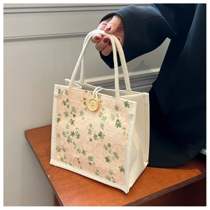 Close-up of floral lace detail and wooden button on a beige canvas lunch tote bag