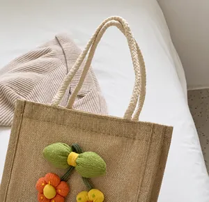 Detail of sturdy braided rope handles and colorful floral decor on jute handbag