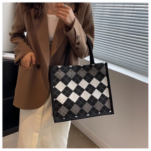 Detail of classic plaid canvas tote bag showing the texture and black woven handles
