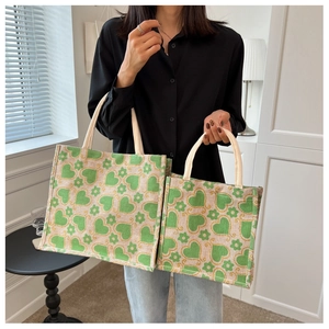 Detail of green floral patterns on large and small canvas tote bags with rope handles