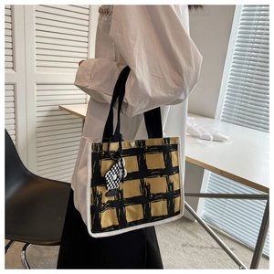 Detail of yellow plaid canvas tote with magnetic buckle and checkerboard charm
