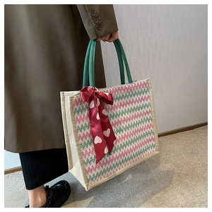 Détail d'un sac cabas en lin beige avec motif en V et foulard décoratif en soie rouge