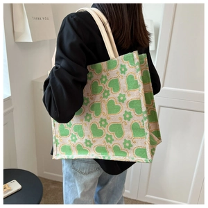 Rear view of a model carrying a green heart print canvas tote bag with rope handles