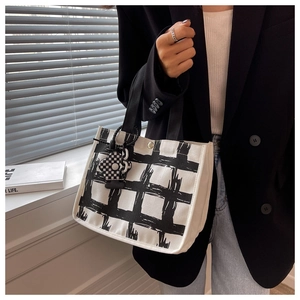 Detail of minimalist canvas handbag with black and white plaid pattern and metal clasp