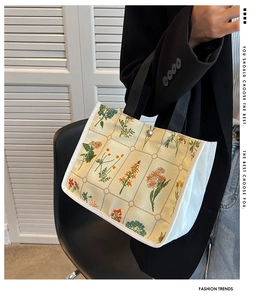 Detail of canvas handbag featuring floral grid pattern and secure metal snap closure