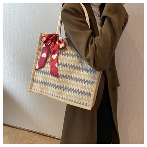 Détail du sac fourre-tout en lin tissé en zigzag avec un nœud en soie rouge à motifs cœurs