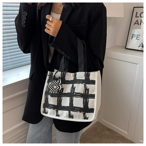 Detail of canvas tote bag with hand-drawn grid pattern and floral charm pendant