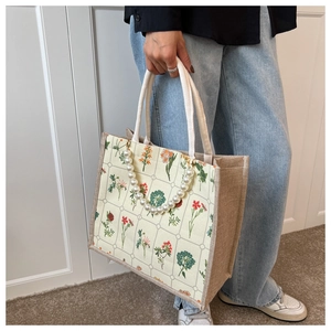 Floral canvas tote with jute sides and oversized pearl chain detail shown on a model